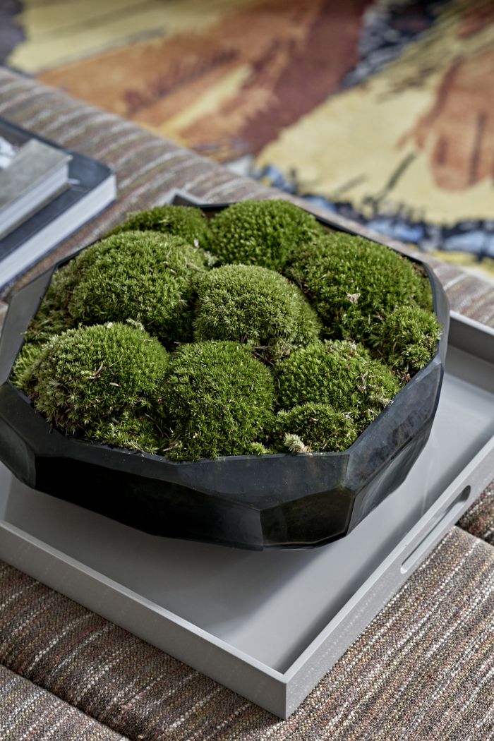 A coffee table arrangement with books, tray and glass bowl with moss. 