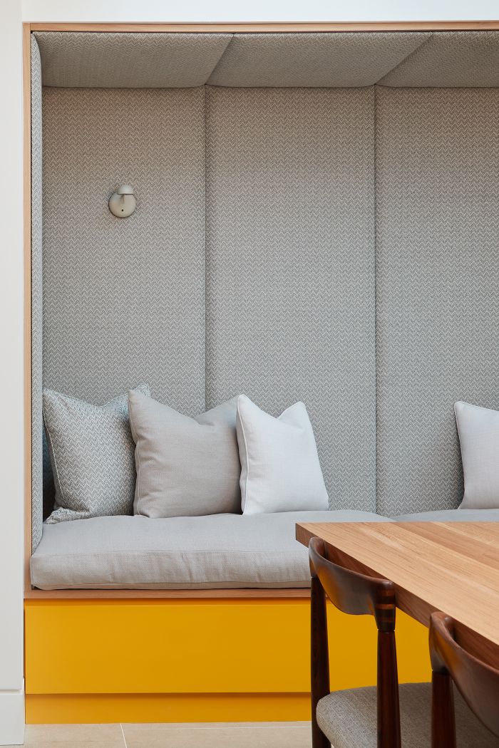 A cosy reading nook in the kitchen with bright sunflower lacquered cabinets. 