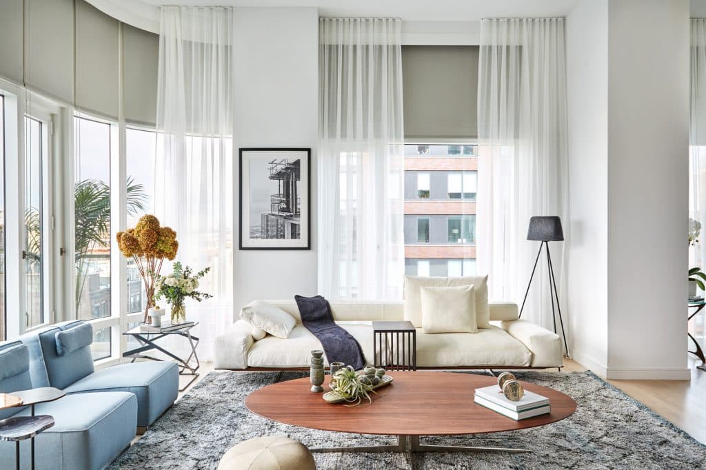 Modern apartment with lots of natural light, decorated with flexform wing sofa and stark silk rug.