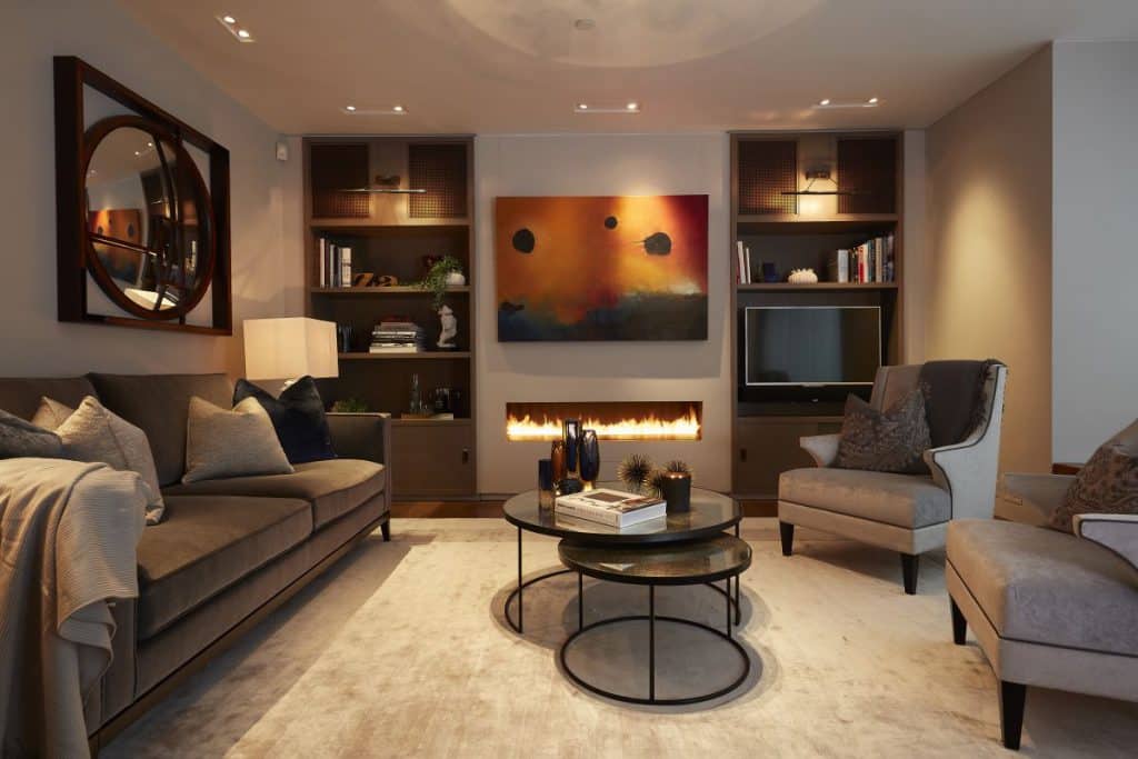 A warm and inviting living room with sofa and two armchairs in soft deep blue and grey tones.