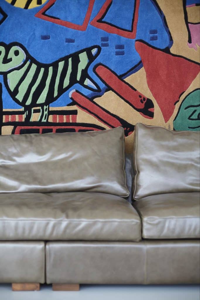 Leather sofa in front of a colourful danish wall tapestry.