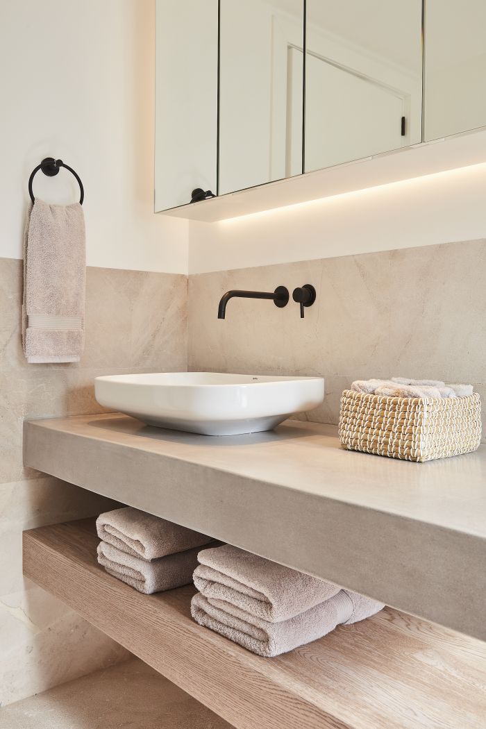 Neutral hardwearing guest bathroom with stone, wood and micro cement. 