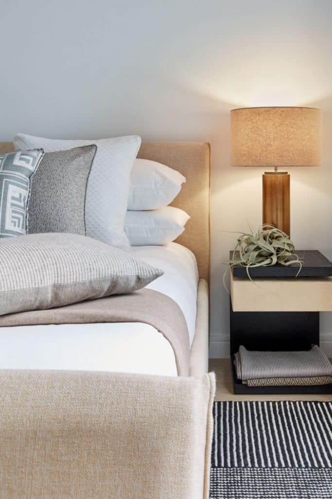 A calm and neutral beige bedroom scheme with a leather and wood bedside table.