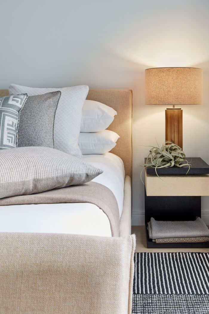 A calm and neutral beige bedroom scheme with a leather and wood bedside table. 