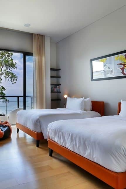 Orange leather bed frames in a twin bedroom with sea views and wooden flooring. 