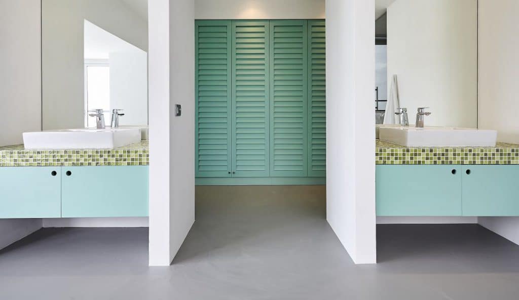 A teal and crisp white coloured double vanity bathroom and walk in wardrobe.