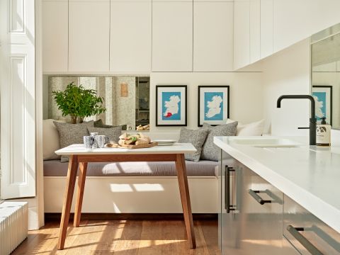 White and grey galley kitchen with high ceilings and sash windows. The space is light and filled with neutral tones.