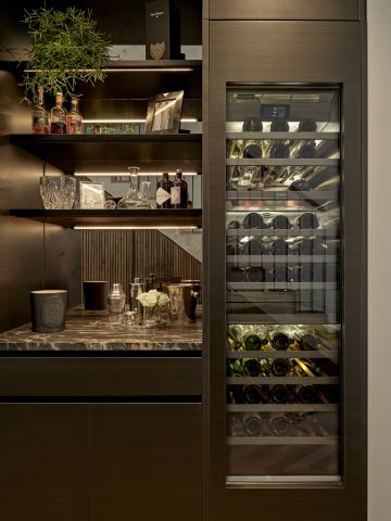 Luxury moody home bar with wine fridge next to it.