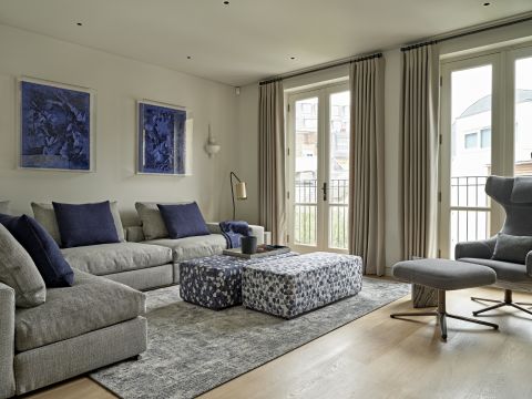 Modern media room with double french doors and flexform groundpiece sofa. In the room the primary colours are neutrals and navy blue.