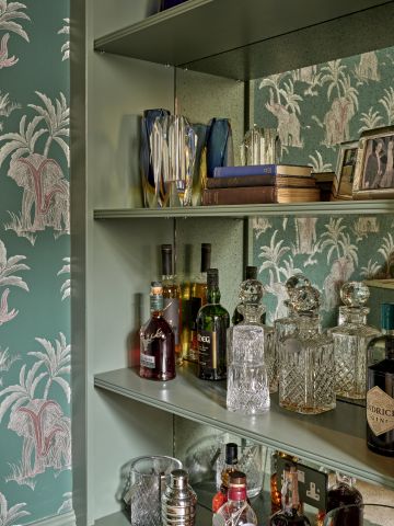 Shelving unit and bar next to fireplace. Shades of green are dominant in this space.