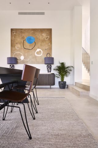 High ceiling dining room with statement art piece above drinks console.