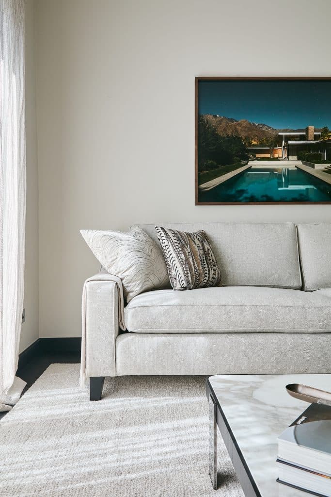 Neutral living space with colourful artwork above sofa.