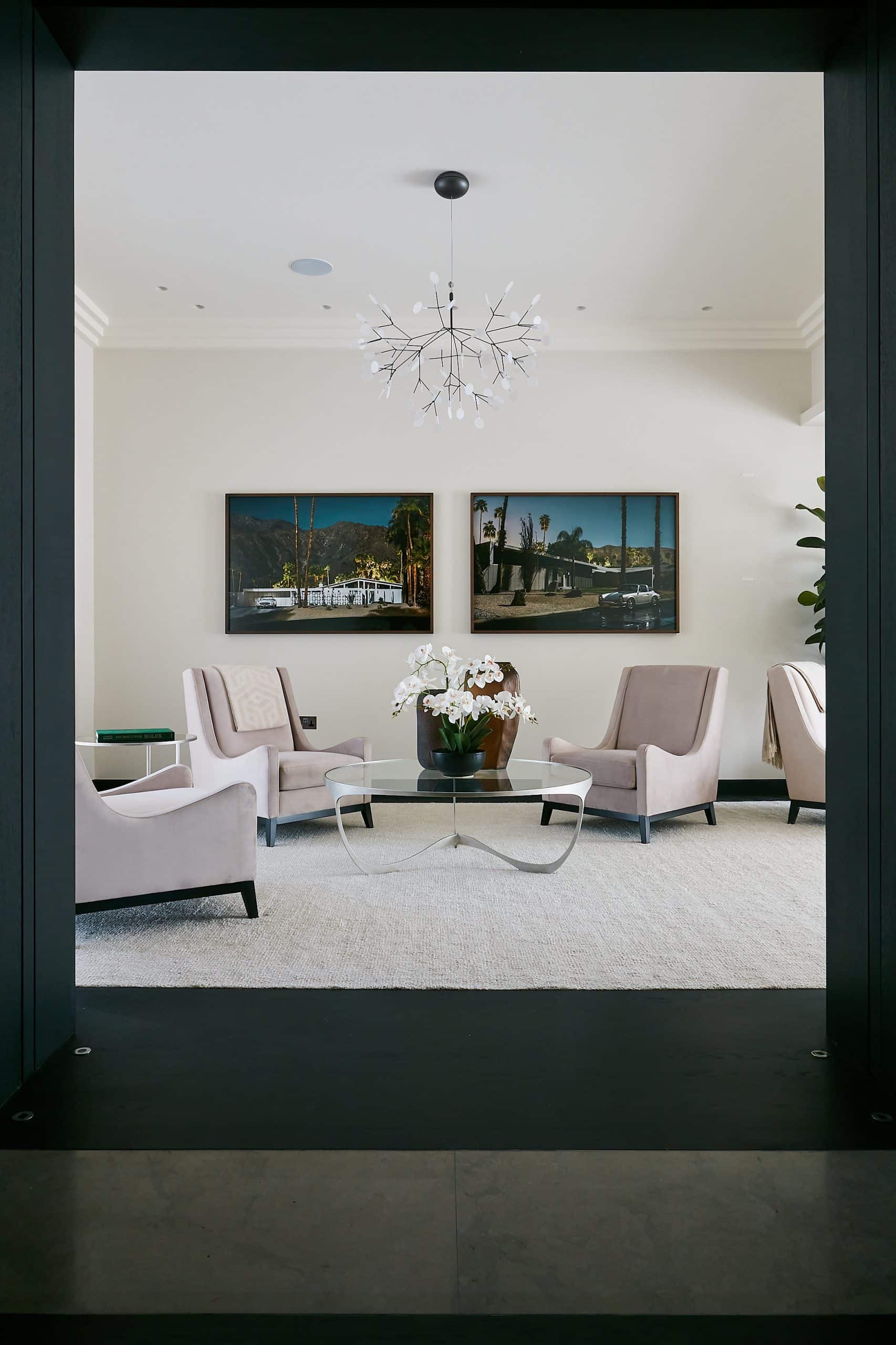 Blush pink armchairs around a glass coffee table in reception room.