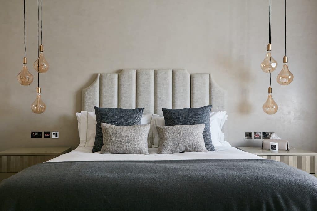 Relaxing neutral bedroom with unique pendant light above the bedside cabinets.