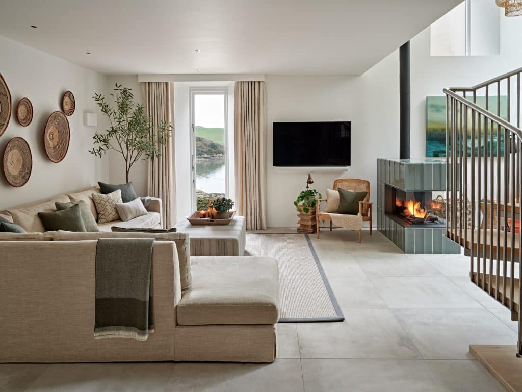 Neutral living space with green tiled fireplace in coastal style house.