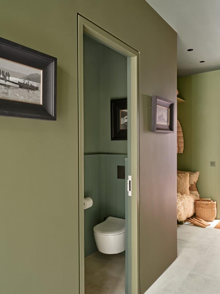 Sage green guest bathroom in coastal style house.