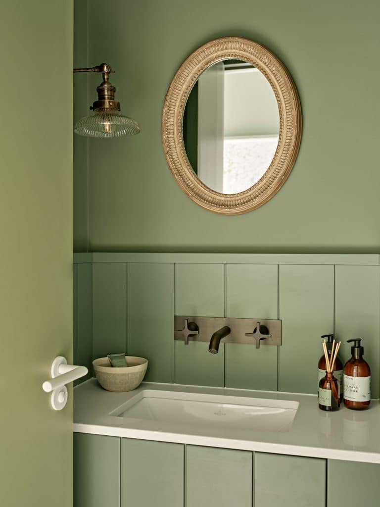 Sage green guest bathroom in coastal style house.