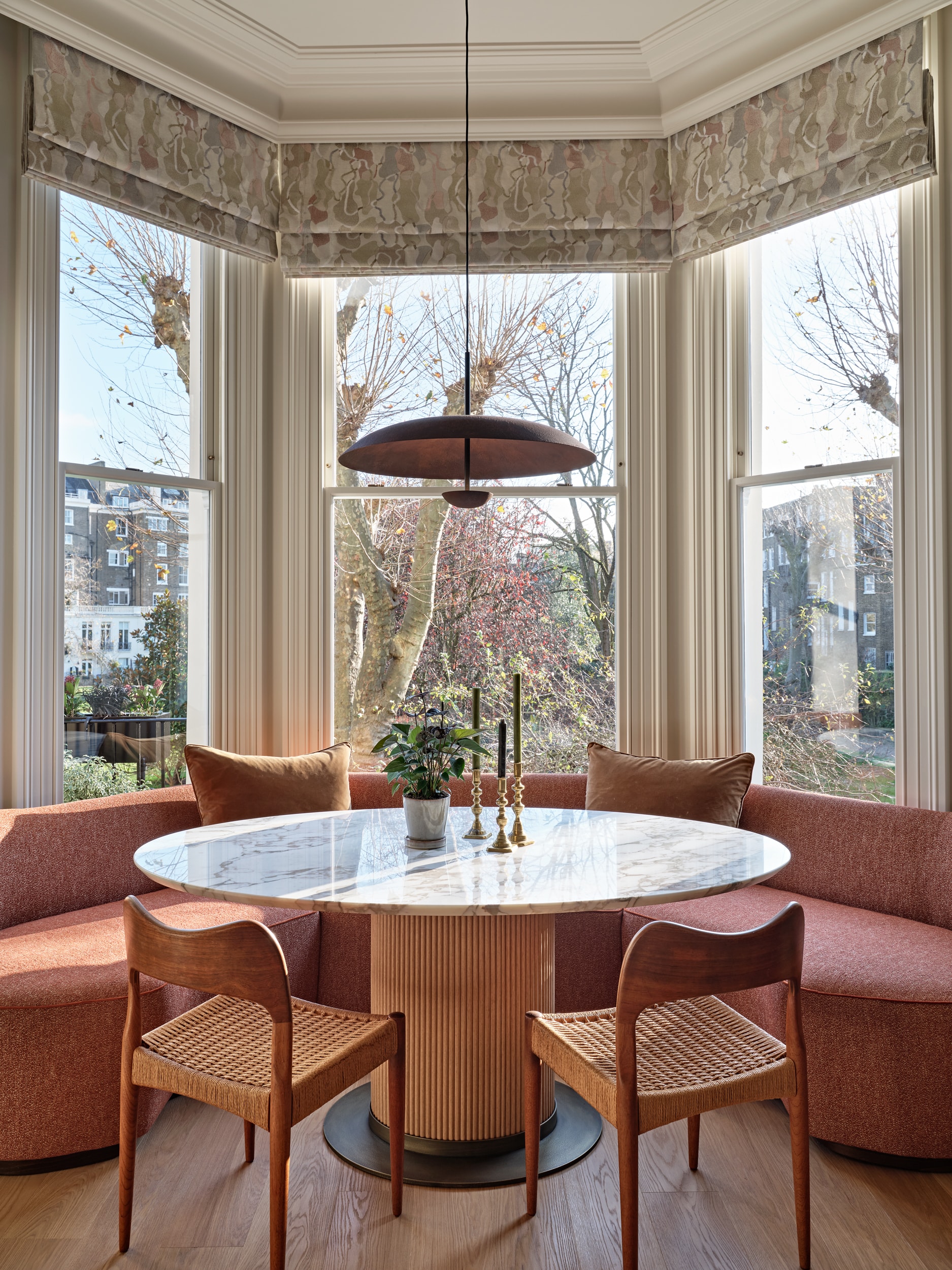 Dining table and chairs in open plan living and dining space. On one side of the dining table a banquette seating is placed.