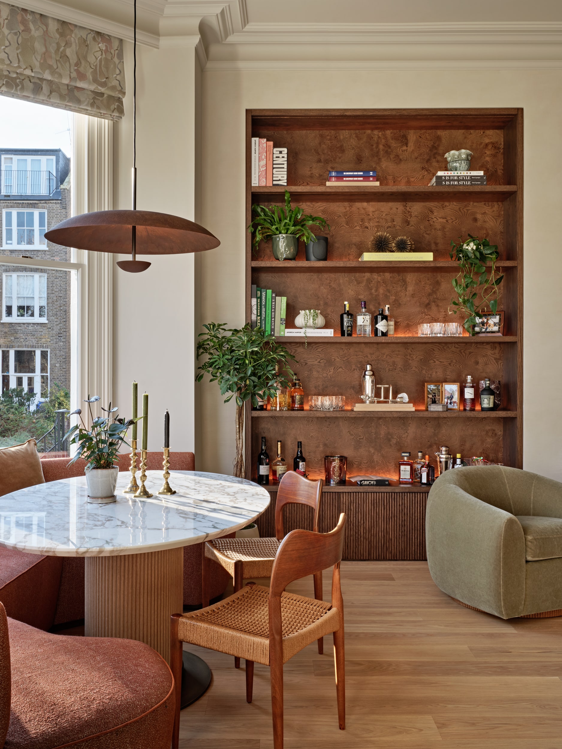 Dining table and chairs in open plan living and dining space. On one side of the dining table a banquette seating is placed.