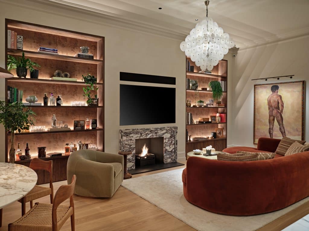 Cozy living space in Central London apartment.On the two sides of the TV and Fireplace there are bespoke shelves displaying sentimental items lovingly collected by the owner.