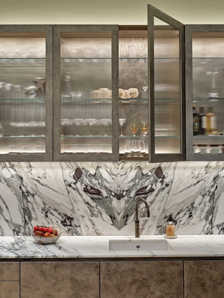 Marble kitchen counter and hand-painted pitted champagne liquid leaf finished cabinets.